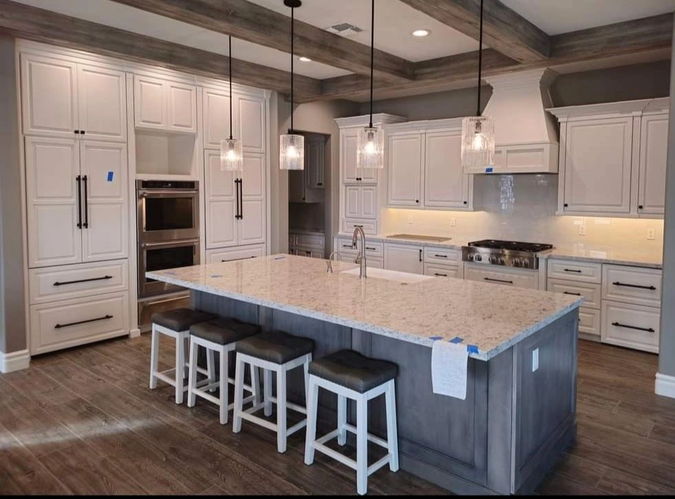 Kitchen with white custom cabinetry, an island with pendant lighting, and a wood beam ceiling